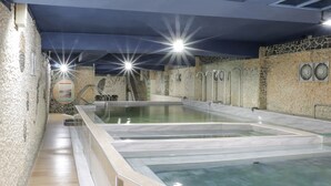 Un jacuzzi con agua cristalina, una pared de piedra y una escalera que sube a un nivel superior.
