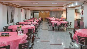 A dining area with multiple tables covered in pink tablecloths, arranged in rows.