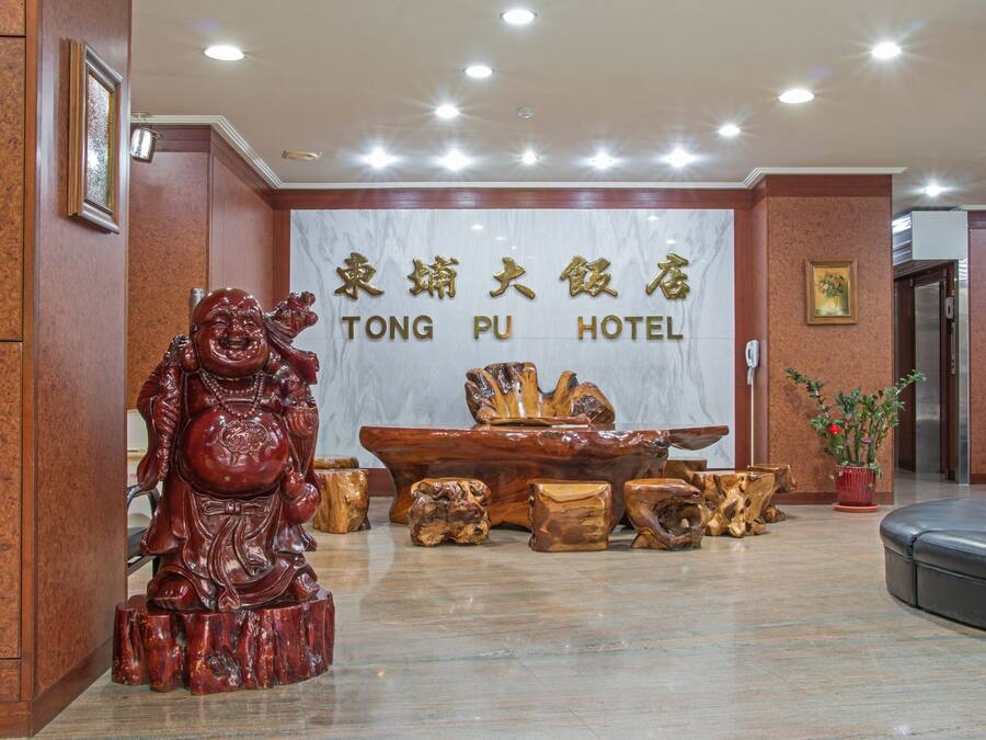 A reception area with a wooden statue, a large wooden table, and a sign that reads "TONG PU HOTEL".