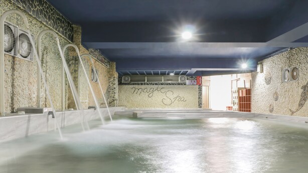 Una piscina interior con pared de piedra y un cartel que dice "Magic Spa".