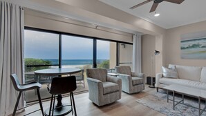 Amplia sala de estar con balcón vistas al mar, amoblada con un sofá, sillones y una mesa de comedor.
