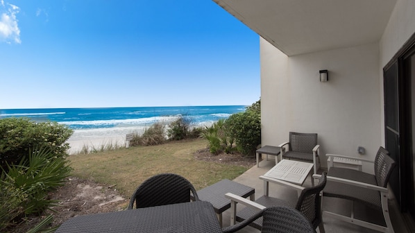 A patio with wicker furniture overlooking a beach.