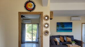 A living room with a dark sofa, a wooden coffee table, and a painting of a beach scene.