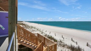 Un escalier en bois mène à une plage d’où l’on a une vue dégagée sur l’océan.