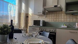Une cuisine moderne avec un coin repas, comprenant une cuisinière, un four à micro-ondes et une grande fenêtre avec des rideaux.