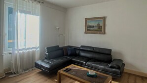 Un salon avec un canapé en cuir noir, une table basse en bois et un tableau accroché au mur.