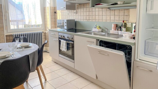 Une cuisine moderne avec un coin repas, comprenant une cuisinière, un four, un four à micro-ondes et un lave-vaisselle.