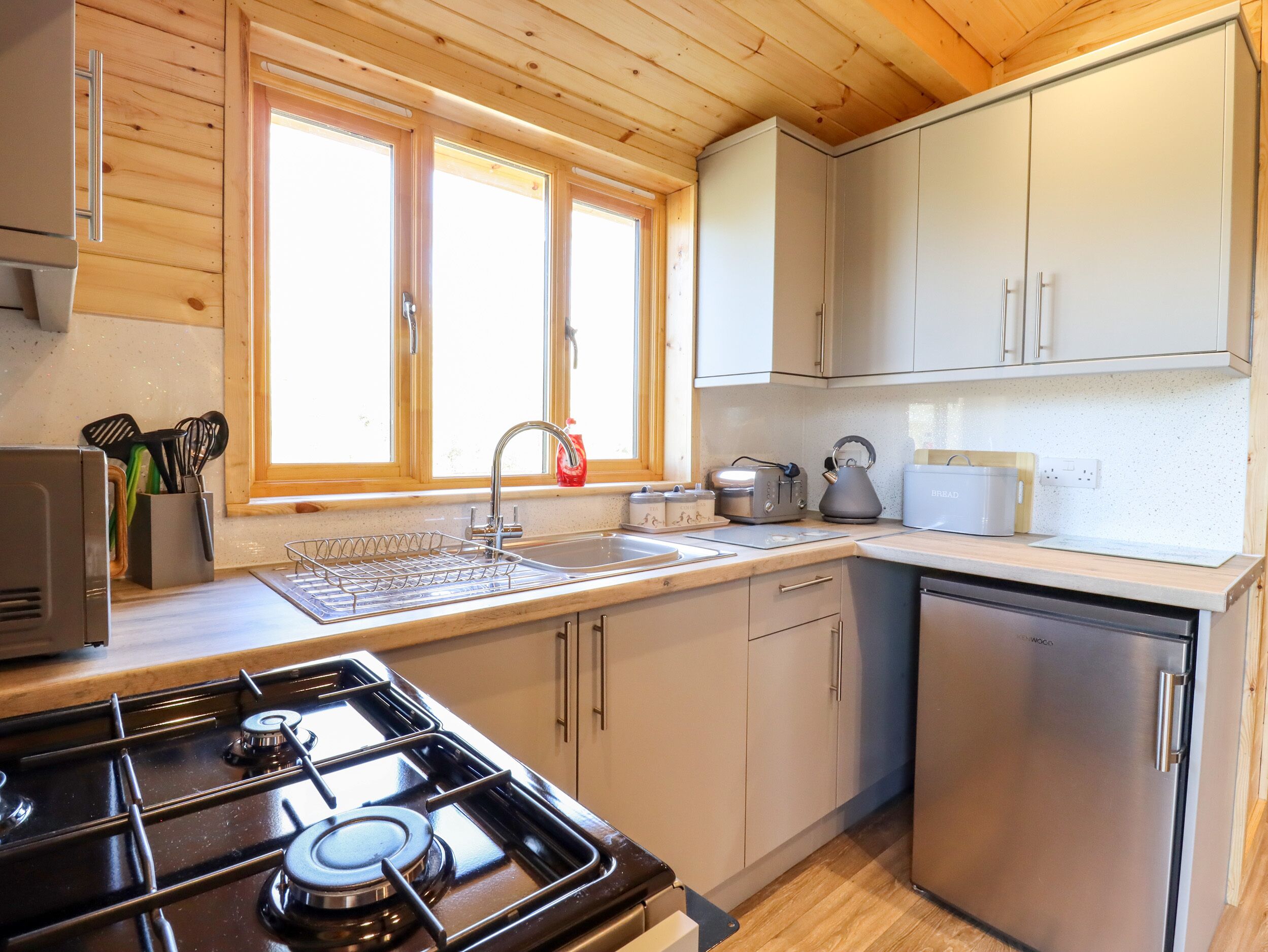 A modern kitchen with a gas stove, stainless steel appliances, and wooden cabinetry.