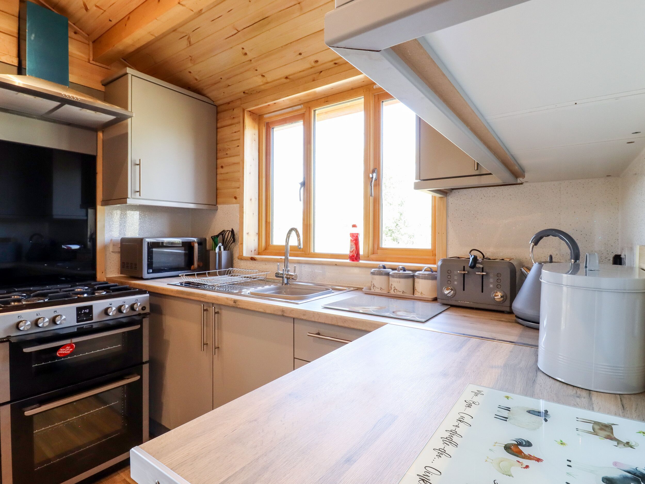Une cuisine équipée de meubles en bois, d’une cuisinière, d’un four à micro-ondes, d’un grille-pain et d’une bouilloire.