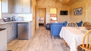 A wooden cabin with a kitchen, dining area, and a sleeping loft. - Clover Lodge (Leiston)