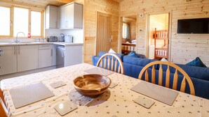 A wooden cabin interior with a kitchen, dining area, and living space. - Clover Lodge (Leiston)