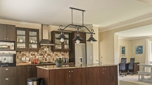 A modern kitchen with dark wood cabinets, a central island, and pendant lighting. - Vitamin Sea (Plettenberg Bay)