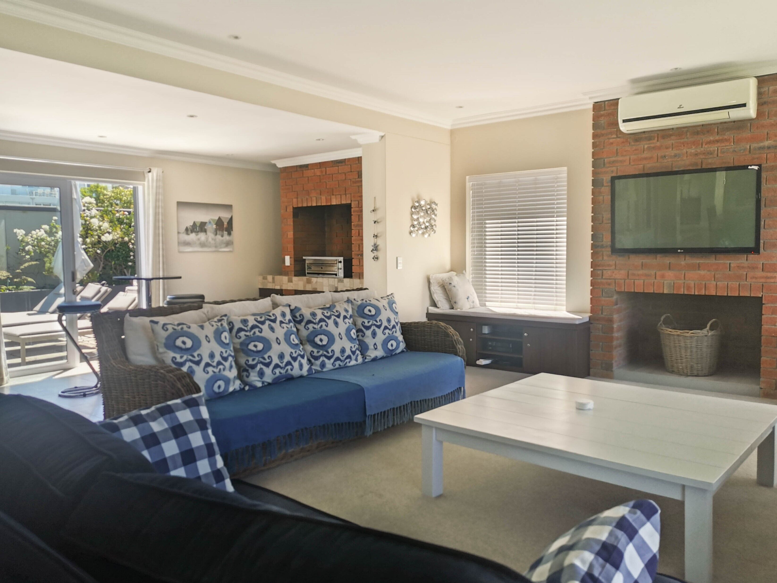 Una sala de estar con sofá, una mesa de centro, chimenea y televisor montado en la pared.