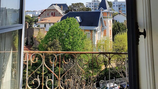 A balcony with a wrought iron railing overlooking a residential area with houses and trees. - Beautiful renovated apartment, 5 min from the beach! (BIARRITZ)