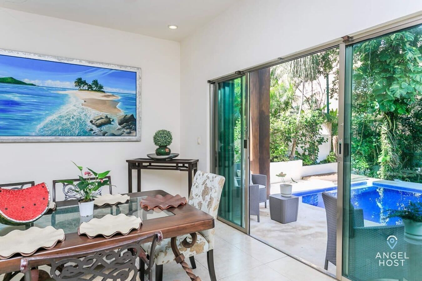 A dining area with a table, chairs, and a painting of a beach scene.