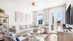 Un salon moderne avec un canapé d’angle, une table basse et un téléviseur posé sur un meuble en bois.