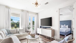 Un salon moderne comprenant un canapé, des fauteuils, une table basse, un téléviseur et un lit.