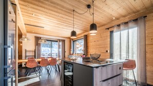 Eine moderne Küche mit Holzausstattung, einer zentralen Kochinsel und Pendelleuchten.