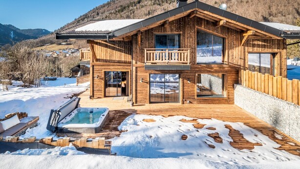 Eine Holzhütte mit Balkon, Whirlpool und Bergblick.