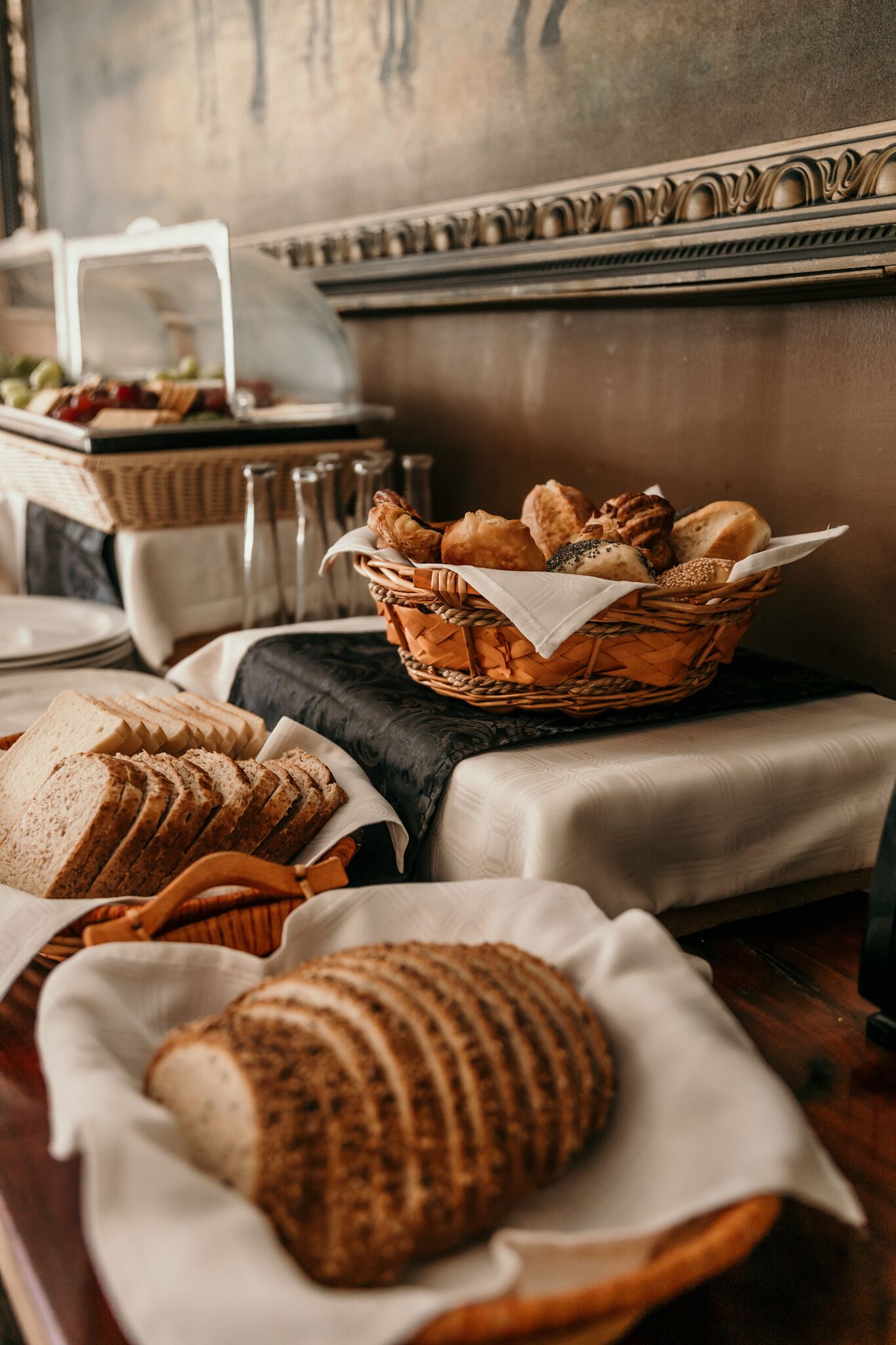 Una mesa con pan en rodajas y una cesta de panes variados.