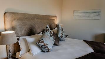 A neatly made bed with a headboard, a bedside lamp, and a painting on the wall.