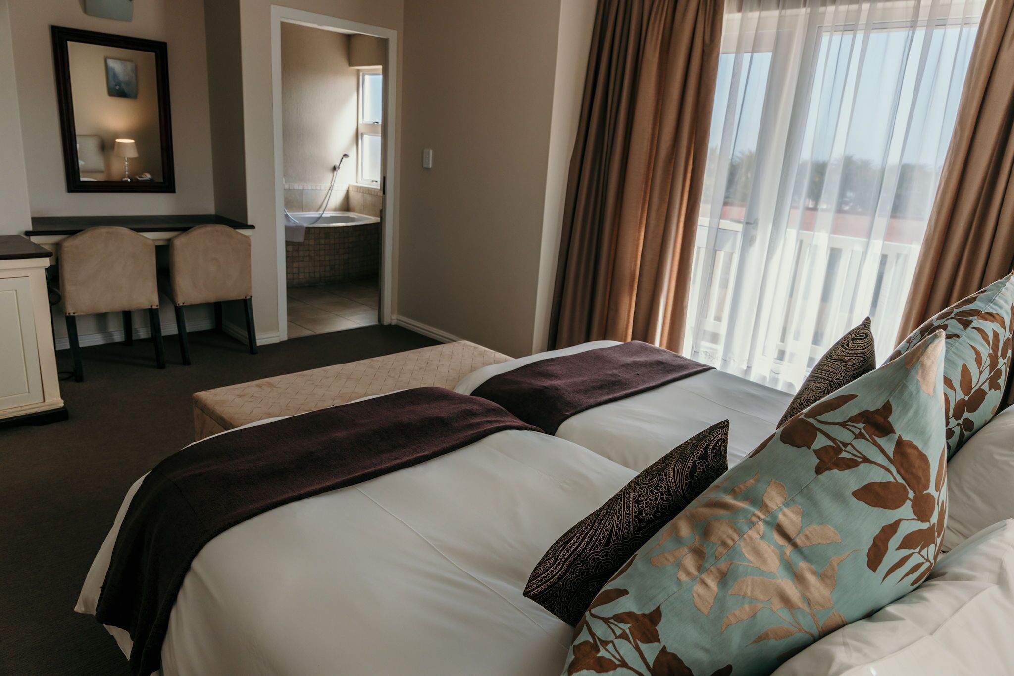 A hotel room with two beds, a desk, and a chair.