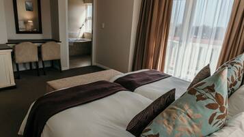 A hotel room with two beds, a desk, and a chair.