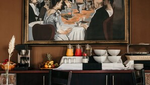 A dining area with a table set for a meal, a coffee machine, and a fruit basket.