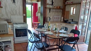 Uma cozinha com mesa de jantar posta para quatro pessoas, fogão e geladeira.