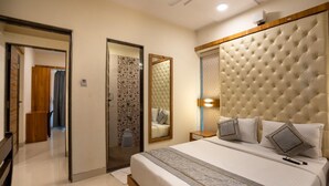 Une chambre à coucher avec un grand lit, un miroir, une table de chevet et une porte donnant sur une autre pièce.