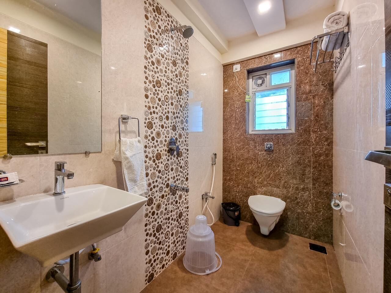 A bathroom with a sink, toilet, shower, and a window.