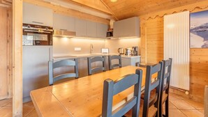A wooden interior with a kitchen, dining area, and a view of a snowy landscape.