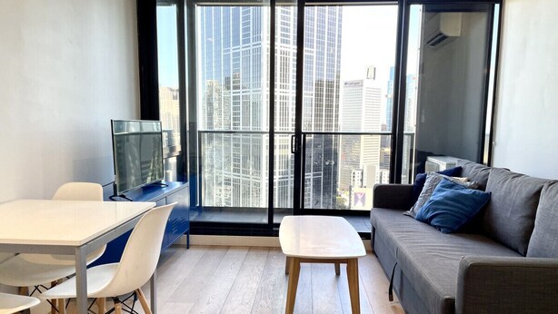 A modern living room with a sofa, a dining table with chairs, and a TV.