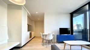 A modern living space with a kitchen, dining area, and a large window offering a view of the city.