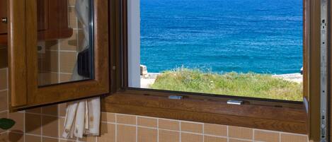 Cozinha com pia, armários de madeira e janela com vista para o oceano.