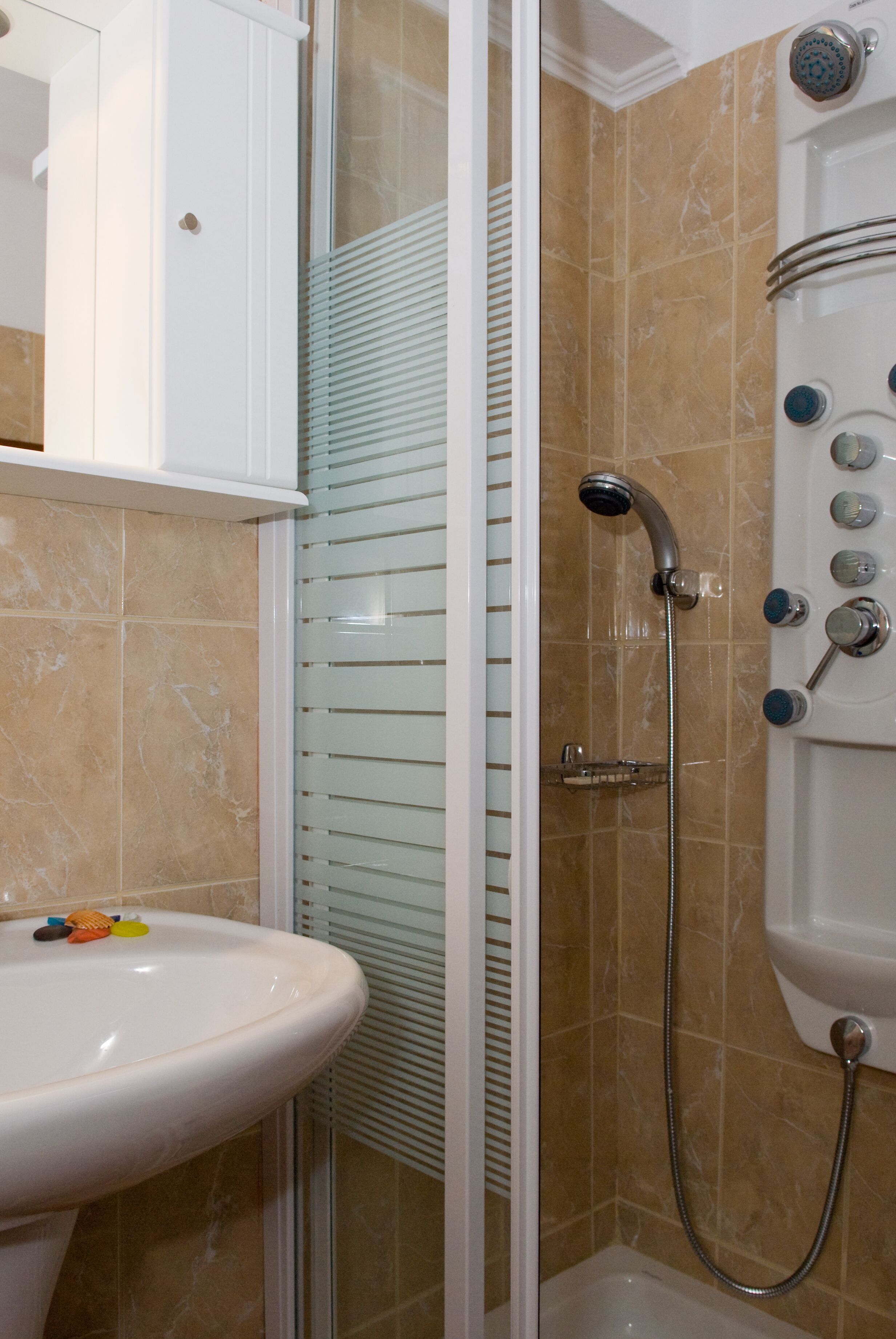Un bagno con box doccia in vetro, lavandino e water.