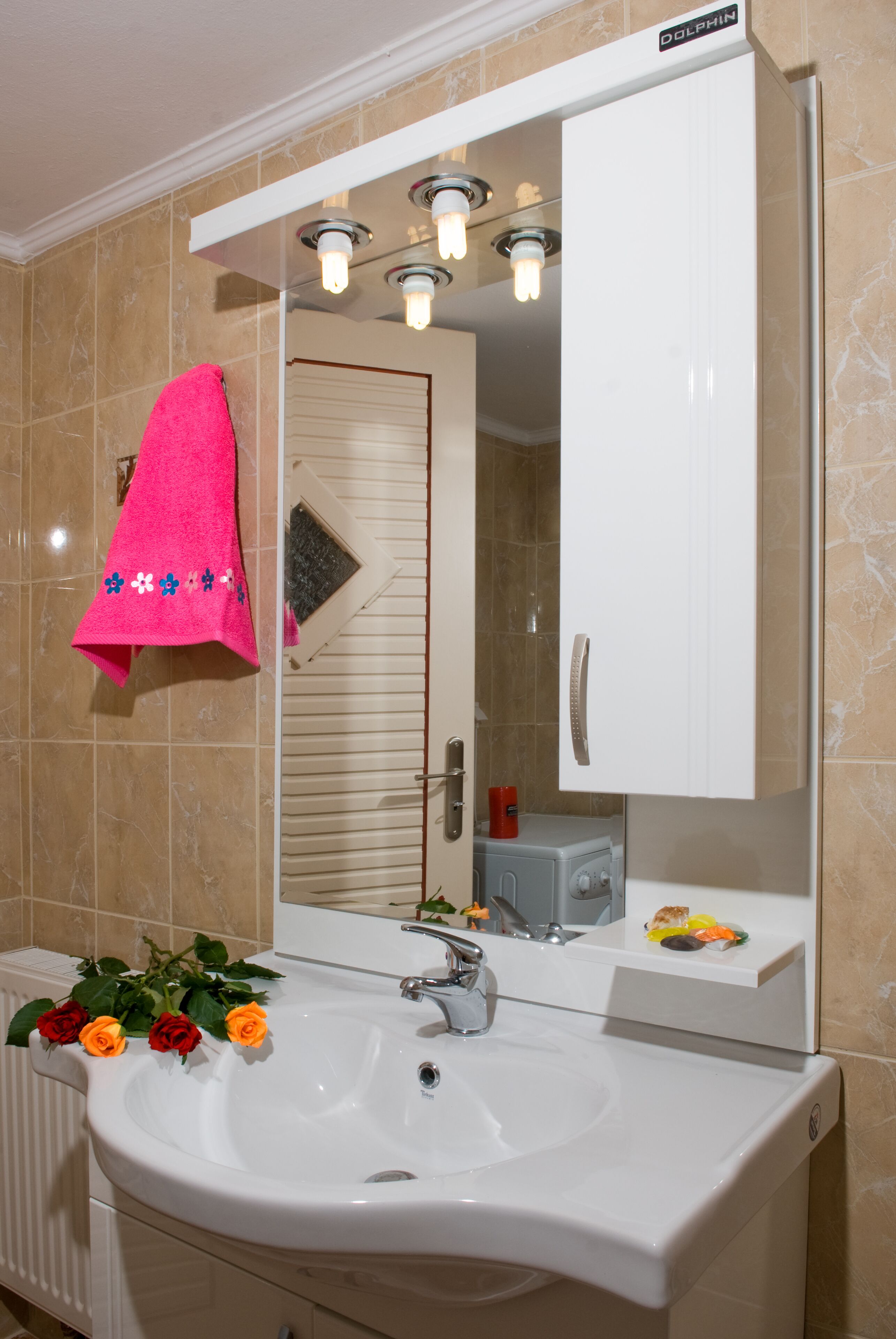 A bathroom with a white sink, a mirror, and a towel rack with a pink towel.