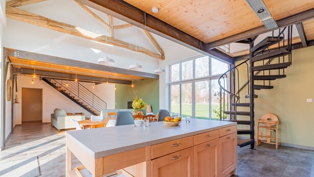 A spacious kitchen with a large island, wooden beams, and a spiral staircase. - Gîte un Air de Campagne (Gergny)