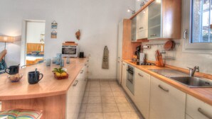 A modern kitchen with a wooden countertop, stainless steel sink, and a built-in oven. There is a small island with a bowl of lemons and a basket of oranges. - Kazamasavani - Belle maison proche mer ! (Cervione)