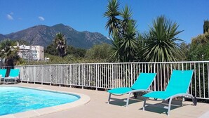 A pool area with lounge chairs and a view of mountains. - Kazamasavani - Belle maison proche mer ! (Cervione)