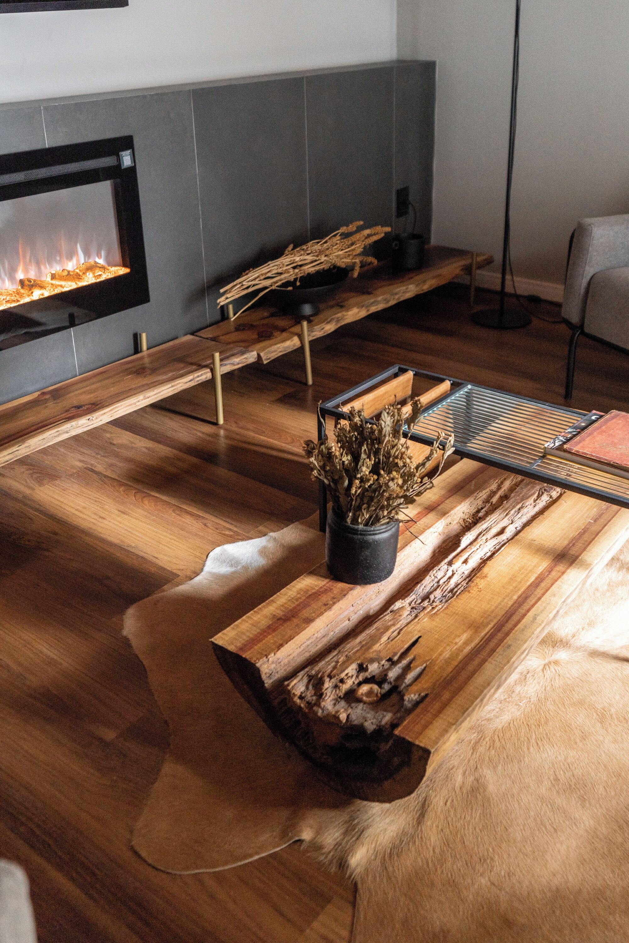 Una sala moderna con chimenea, muebles de madera y un pouf de cuero.