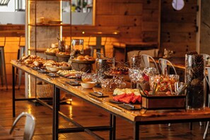 A long wooden table with various food items and glassware, set in a room with wooden walls and metal chairs. - Jangal das Araucárias Swan Design Hotel Canela (Canela)