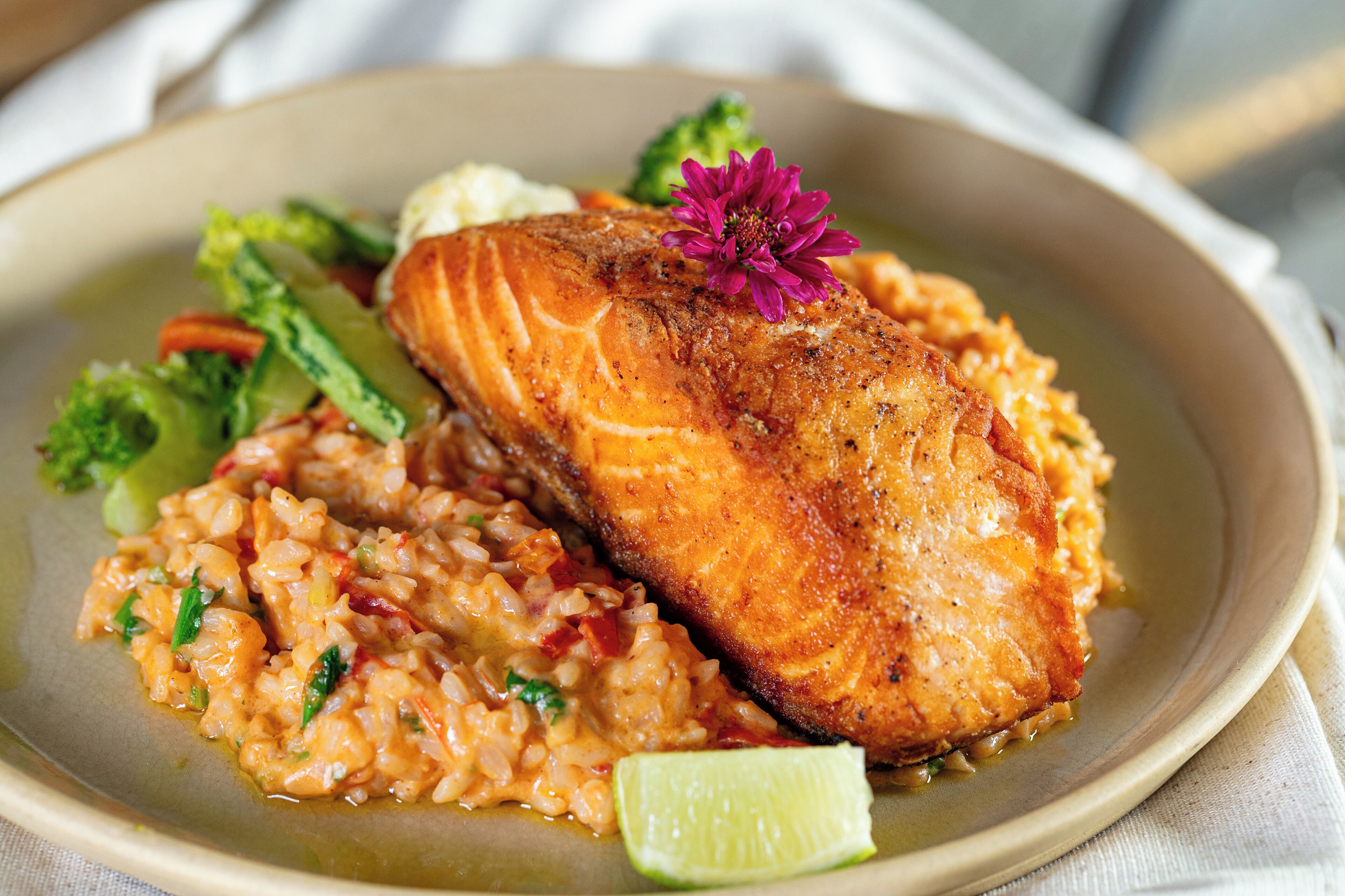 A plate with salmon, rice, broccoli, and a lime wedge.