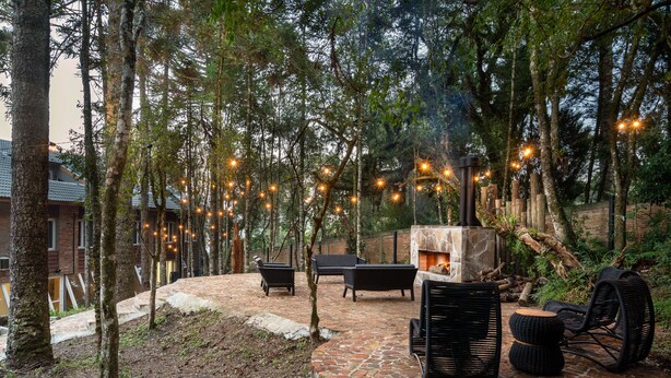 An outdoor patio with stone flooring, wicker furniture, and string lights. - Jangal das Araucárias Swan Design Hotel Canela (Canela)