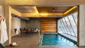 A modern indoor pool area with a wooden wall and large windows. - Jangal das Araucárias Swan Design Hotel Canela (Canela)