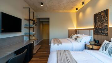 Une chambre d’hôtel moderne équipée de deux lits, d’un téléviseur à écran plat, d’un bureau et d’une grande œuvre d’art abstraite accrochée au mur.