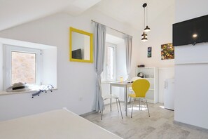 A bright, modern room with a dining area, a small kitchen, and a window with a view.