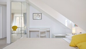 A modern bedroom with a bed, a desk, and a chair. There is a large mirror on the wall and a picture frame. - Room Nino 2 - One Bedroom Apartment, Sleeps 2 (Dubrovnik)