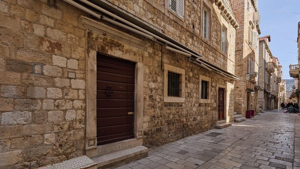A stone building with a large wooden door and a bench outside.