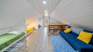 A compact, well-lit room with a bunk bed, a sofa with yellow pillows, and a small table with items on it. - Cabin w/ Hot Tub on Small Pond (Rockwood)